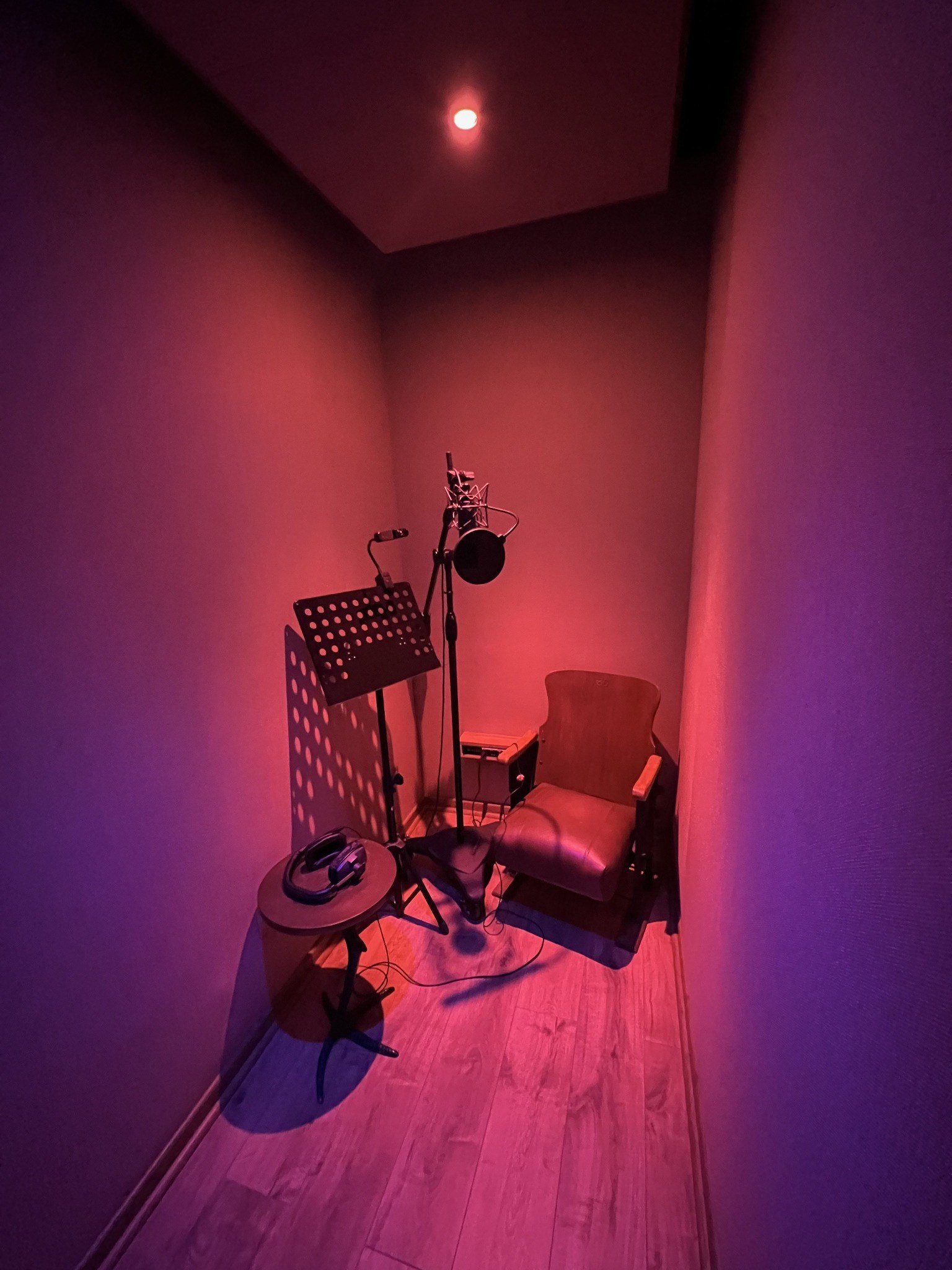 Cabina de voces con micrófono e iluminación roja y violeta